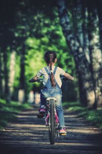 Rear view of woman riding bicycle on road