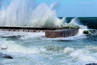 Waves splashing on sea against sky