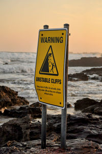 Warning sign on a beach with amazing sunset in the background with waves