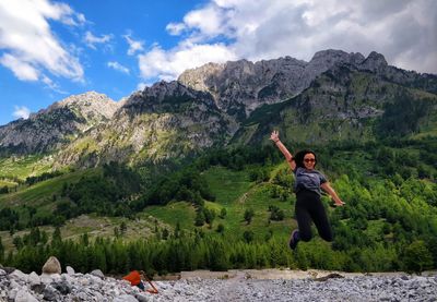Full length of happy young woman in mountains against sky