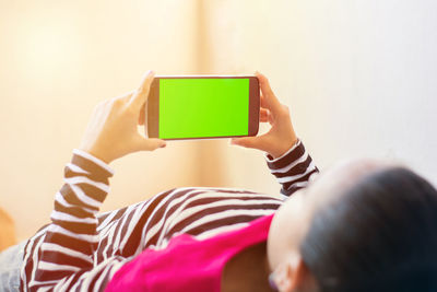 Rear view of boy photographing with mobile phone