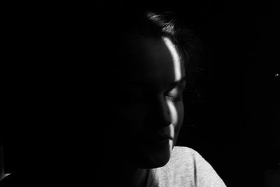 Close-up portrait of young woman against black background