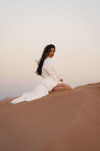 Portrait of young woman standing on sand at beach