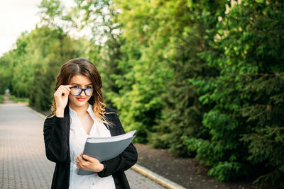 Portrait of young woman standing on mobile phone