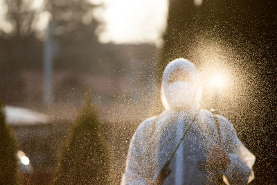 Rear view of man standing on wet statue during rainy season