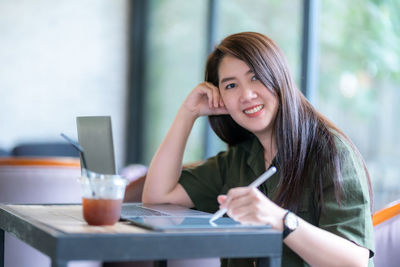Young woman using mobile phone while sitting on table