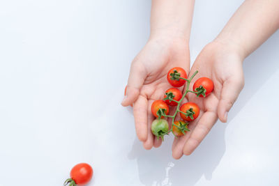 Cropped image of hand holding strawberry against white background