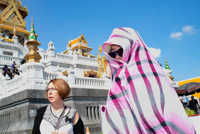 Young woman standing outside temple against sky