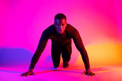 Full length of young man against pink background