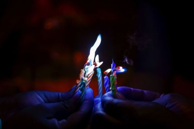 Close-up of people holding burning candles