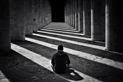 Rear view of man sitting in corridor of historic building