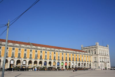 Group of people in front of building against clear blue sky