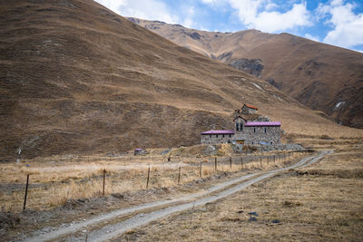 Scenic view of road by mountains against sky