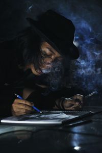 Man smoking cigarette while writing in book