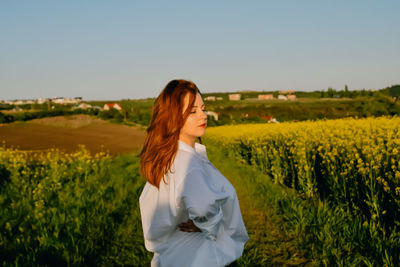 Rear view of woman standing on field against sky