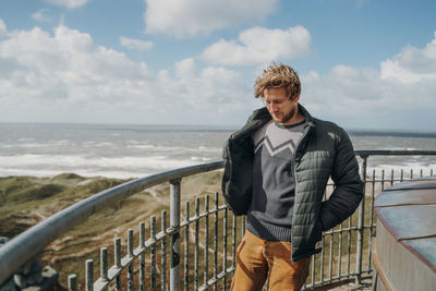 Young man wearing warm clothing against sea