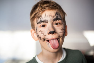 Portrait of boy sticking out tongue with painted face