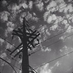 Low angle view of power lines against cloudy sky