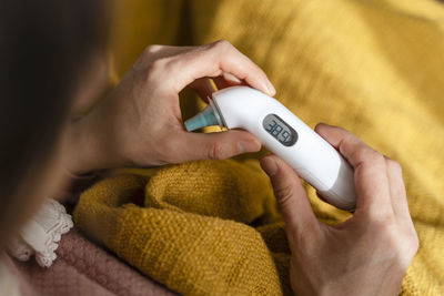 Woman checking temperature with thermometer at home