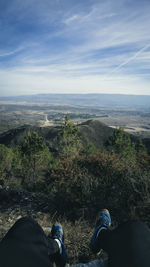 Low section of people on mountain against sky