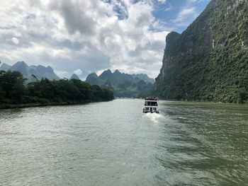 Boat sailing on sea against mountains