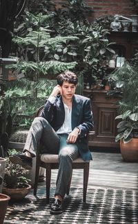 Portrait of young man sitting on chair against plants