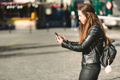 Side view of woman using smart phone on street