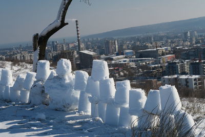 Snow covered buildings in city against sky