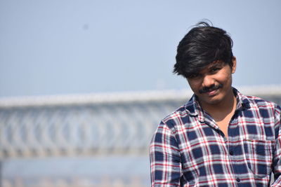Portrait of young man standing against sky