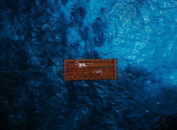 Directly above shot of bikini women lying on wooden raft in sea