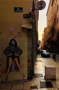 Young woman on street by footpath against buildings in city