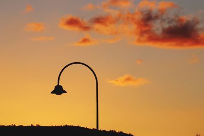 Silhouette street light against orange sky