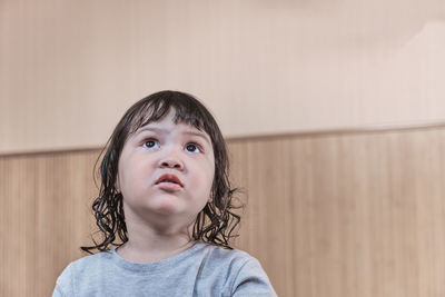 Close-up home portrait of little asian girl with black hair looking up in surprise