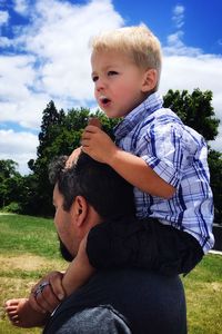 Father and son on field against sky