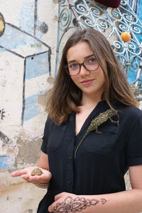 Portrait of young woman with young tortoise and chameleon against wall