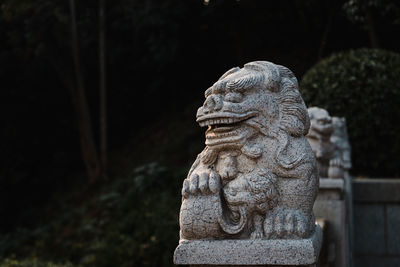 Close-up of stone lion statue against trees