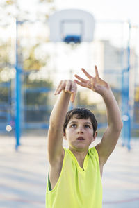 Portrait of boy with arms raised standing outdoors