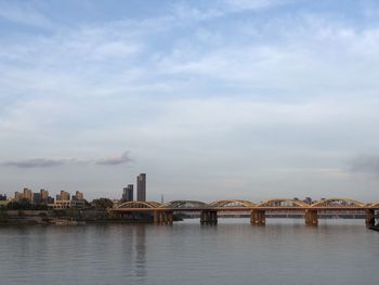 Bridge over river against sky in city