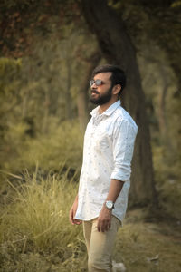 Young man looking away while standing on field