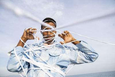 Low angle view of man holding umbrella against sky