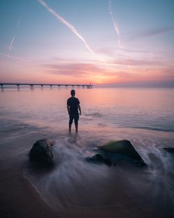 Silhouette person standing on beach against sky during sunset