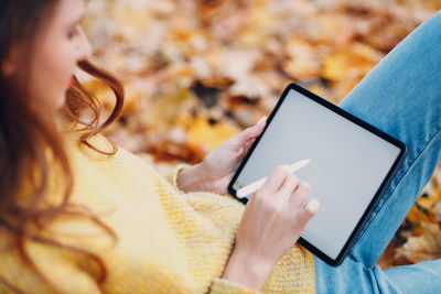 Midsection of woman using digital tablet at park