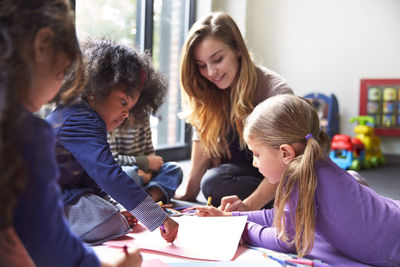 Teacher and students drawing on papers at child care