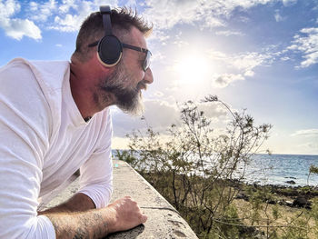 Man wearing sunglasses against sea against sky during sunset