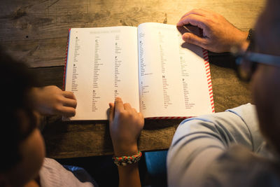 High angle view of father and son reading book in darkroom at home