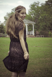 Young woman standing on field against trees