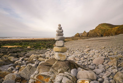 Stack of stones on beach against sky