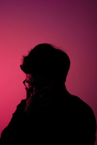 Portrait of silhouette man standing against pink background