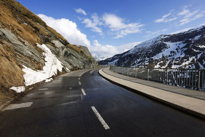 Road by snowcapped mountains against sky