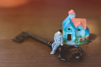 Close-up of key with human figurine and model home on table